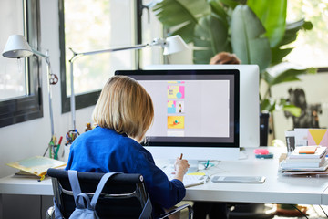 Businesswoman Doing Paperwork By Computer At Desk