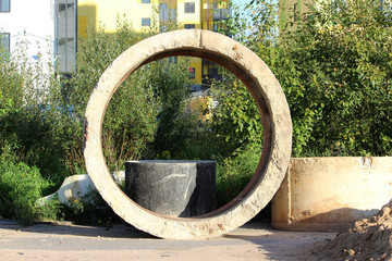 Concrete cylindrical rings for creating storm drains are located near the site where the expansion and repair of the road takes place. Gatchina.