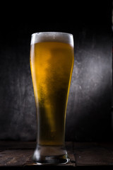 Cold beer glass with condensation and bubbles over grey concrete background