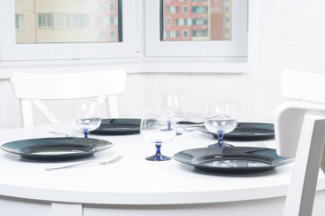Round white table served with plates, forks and glasses
