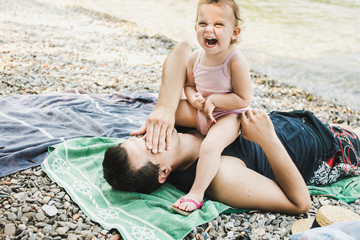 Little toddler sitting on her father's chest laughing