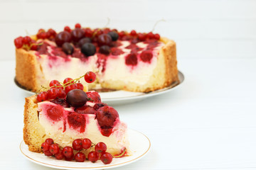 Cake with berries is located on a plate on a white background, piece of cake in the foreground