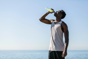 African sporty man drinking isotonic beverage