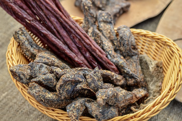 Close up of delicious dry cured salami sausages in rustic basket. Selective focus.