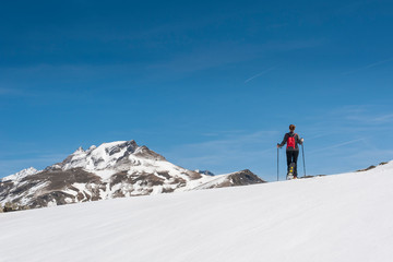 Fototapeta na wymiar A young snowshoe hiker walks through a snowy alpine landscape.