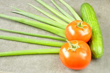 onion cucumber and tomatoes on a gray background