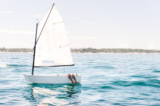 Small sail boat on a flat ocean, waiting for wind