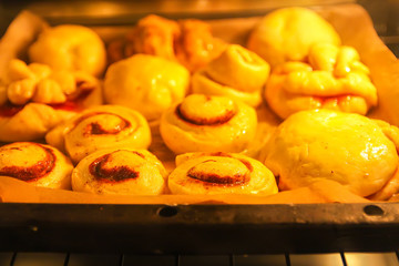 Homemade sweet cinnamon roll baking on a sheet in oven