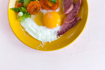 egg, meat, tomatoes, beans on a yellow plate on a white background