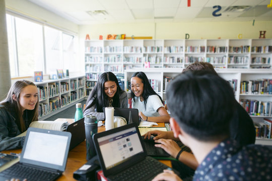 Group of highschool students studying together in library - Powered by Adobe