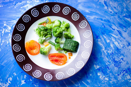beans, broccoli and tomatoes on a plate on a blue background