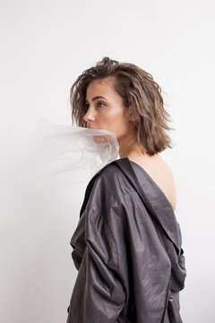 Fashion portrait of young stylish female in grey and semi-transparent plastic
