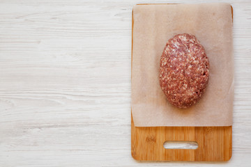 Fresh raw grass fed ground beef on a bamboo board, top view. Copy space.