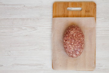 Fresh raw grass fed ground beef on a bamboo board, top view. Flat lay, overhead, from above. Copy space.