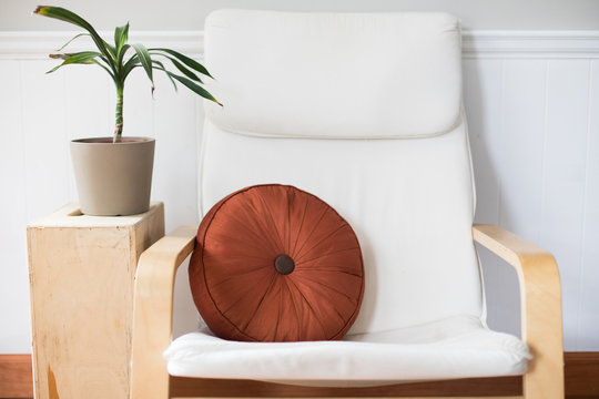 White Chair with Orange Pillow and Plant