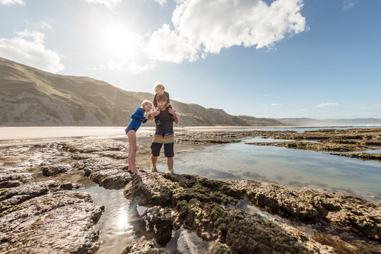 Father showing sea animal to children at tide pools