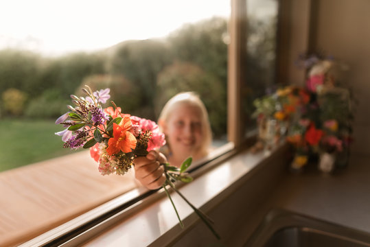 Girl handing flowers through a window on a sunny day