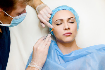 Naklejka premium Woman makes botox injections in eye corner. Doctor cleans the girl's face from wrinkles. Clear crows feet by botox injections. Plastic surgery in private medical clinic.