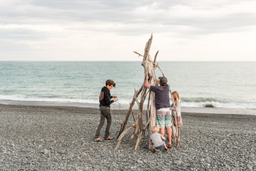 Family decorating driftwood Christmas tree at coast