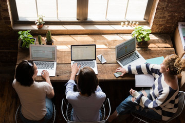 Female co-workers on laptops, shot from above