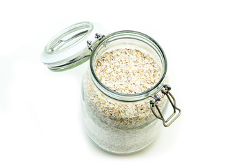 The oat flakes stored inside the closable glass bottle isolated on a white background. 
