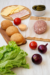 Cheeseburger ingredients on a white wooden table, side view. Close-up.