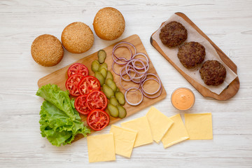Cheeseburger ingredients on a white wooden surface, top view. Close-up.