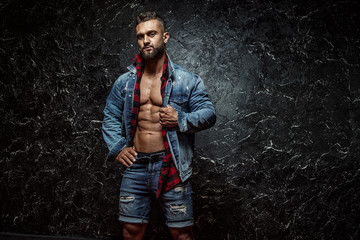 Portrait of strong healthy handsome Athletic Man Fitness Model posing near dark wall