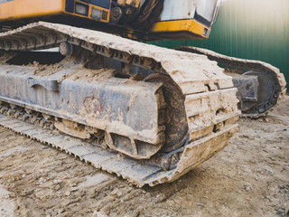 Closeup image of dirty excavator tracks on the building site