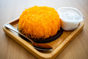 Gold egg yolk thread cake on a wooden plate