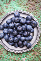 Blueberries on plate on green background 