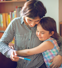 Mother enjoying with her daughter while looking at the positive pregnancy test