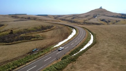 White Taxi driving through beautiful countryside in Wakkanai - Cape Sōya, Hokkaidō, Japan - Aerial view