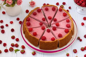 Cheesecake with raspberries is located on a white background