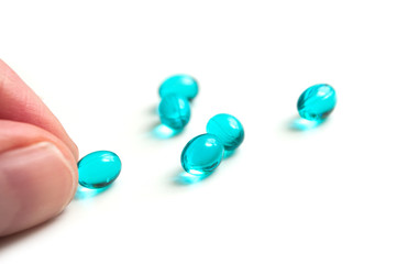 closeup of blue pills in hand on white background