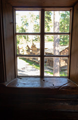 Old authentic 19th century wooden peasant house window with wooden window sill damaged by people and time, and a view of Seurasaari village in Helsinki in Finland on a summer day.