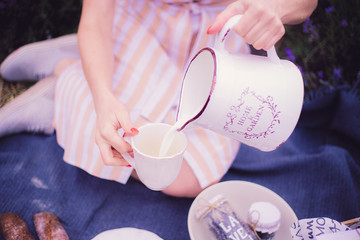 The girl pours milk into a cup on a beautiful background