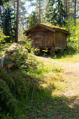 An old authentic 18th century wooden farmhouse in the middle of a forest on Seurasaari island in Helsinki in Finland on a summer day.