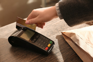 Woman with credit card using payment terminal at shop, closeup