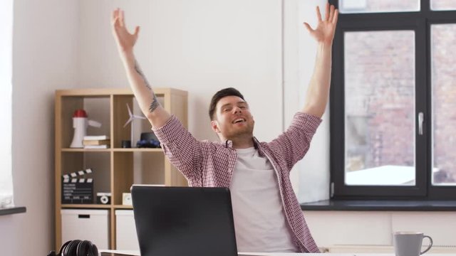technology, internet and people concept - happy young man with laptop computer celebrating success at office