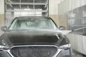 Cleaning automobile with high pressure water jet at car wash