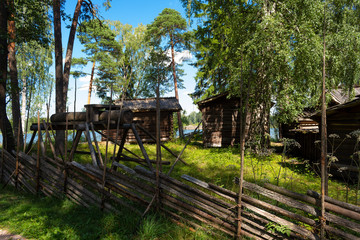 Old authentic wooden buildings of the 18th century, peasant dwellings in the middle of the forest behind the hedge on Seurasaari island in Helsinki in Finland on a summer day.