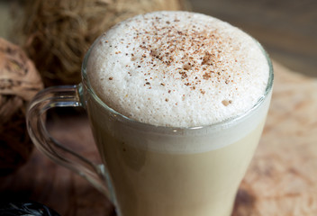 a glass cup of coffee, cappuccino with a frothiness, sprinkled with grated chocolate and cinnamon