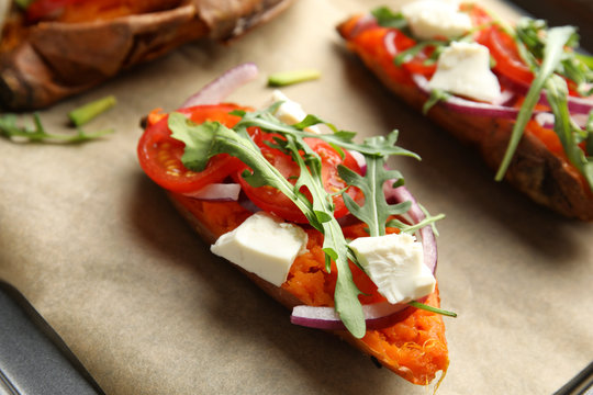 Delicious stuffed sweet potatoes on parchment, closeup