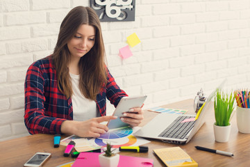Creative designer working on a tablet while using laptop in office