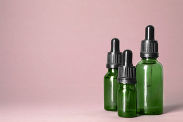 Cosmetic bottles of essential oils on color background. Space for text