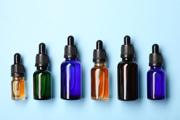 Flat lay composition with cosmetic bottles of essential oils on color background