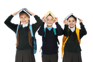 Portrait of funny children in school uniform with books on heads against white background