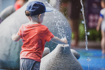 Niño pequeño jugando con agua en un parque de Singapur, Asia. Juego libre con agua. 