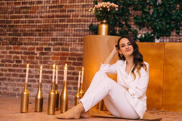 A woman in a white suit sitting on the floor and looking into th